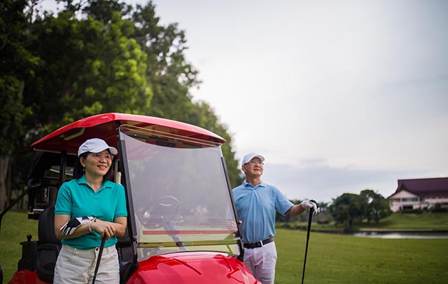 Single Premium Deferred Annuity - older man and woman standing beside a red golf cart while playing golf